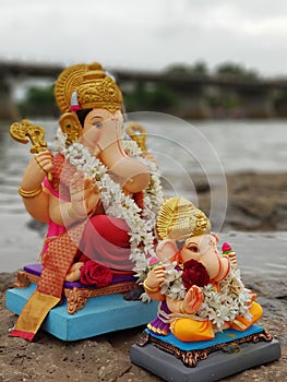 Side view of two ganpati idols ganpati visarjan in river.