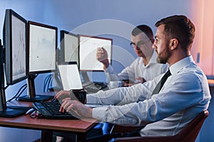 Side view. Two stock traders working in the office with exchange technology