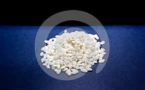 Side view of uncoocked rice grains on the blue and black background