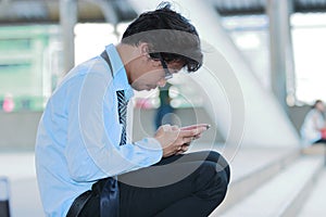 Side view of unemployed stressed young Asian man looking mobile smart phone for find job. Unemployment concept.