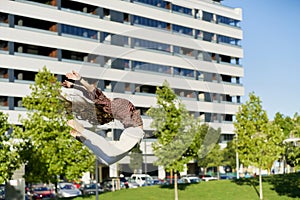 Side view of unrecognizable flexible female dancer showing trick in air near urban building and trees under blue sky