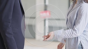 Side view of unrecognizable seller and buyer shaking hands and passing key indoors. Young Caucasian man and woman making