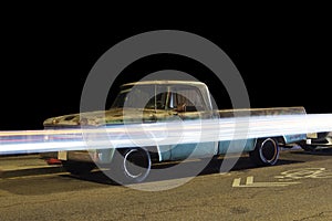 Side view of a vintage classic pick up truck car and light trails caused by traffic in Venice, California at night photo