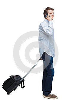 Side view of walking business man with suitcase talking on the phone