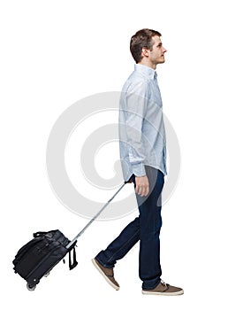 Side view of walking business man with suitcase talking on the phone