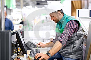 Side view on warehouse worker working on computer