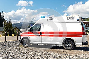 Side view of white ambulance rescue ems van car parked near countryside rural road at highland mountain resort area