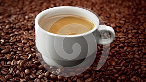 Side view of white cup of black coffe on coffee beans