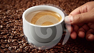Side view of white cup of black coffe on coffee beans