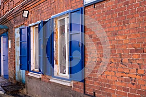 Side view, windows with blue iron shutters on a red brick wall