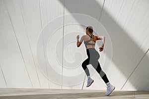 Side view of woman athlete is jogging on morning on modern building background. Healthy life concept