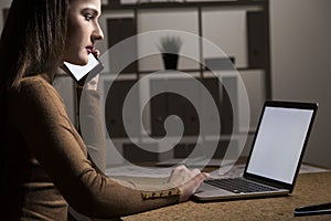 Side view of a woman in a brown turtleneck typing while on the p