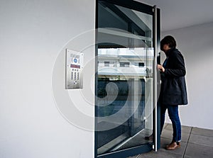 Side view of woman entering apartment building intercom access