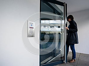 Side view of woman entering apartment building intercom access photo