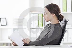 Side view of woman in gray reading in office