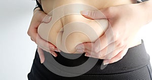 Side view of woman hand catching fat body belly paunch , diabetic risk factor.