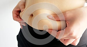 Side view of woman hand catching fat body belly paunch , diabetic risk factor.