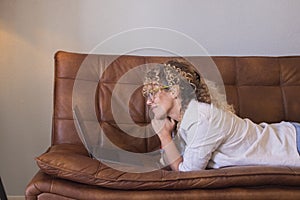 Side view of woman laying on couch smiling and using laptop to chat and surf the web. People an online wireless internet