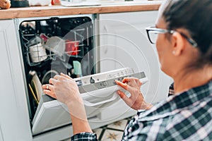 Side view of woman loading dishes into washing machine