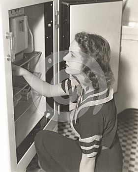 Side view of woman looking through refrigerator