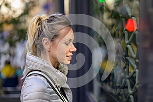 Side view of a woman looking through the window of a shop