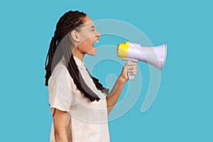 Side view of woman loudly screaming at megaphone, making announce, protesting, wants to be heard.