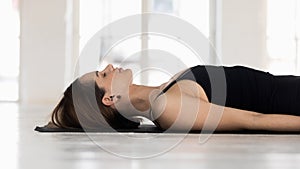 Side view woman doing Shavasana Dead Body Posture indoors