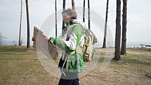 Side view woman with paper map walking in slow motion in wilderness. Caucasian female tourist exploring nature outdoors