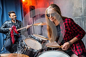 Side view of woman playing drums and man singing into microphone
