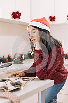 Side view of woman reading recipe book in cooking area