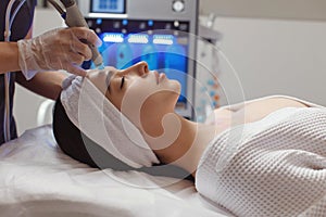 Side view of woman receiving microdermabrasion therapy on forehead at beauty spa