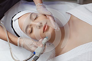 Side view of woman receiving microdermabrasion therapy on forehead at beauty spa