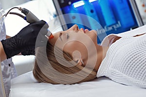 Side view of woman receiving microdermabrasion therapy on forehead at beauty spa