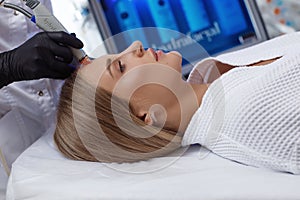 Side view of woman receiving microdermabrasion therapy on forehead at beauty spa