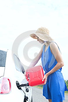 Side view of woman refueling car on country road