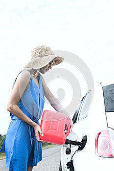 Side view of woman refueling car on country road