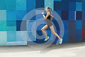 Side view of woman running against bright wall