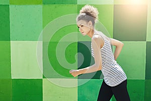 Side view of woman running against bright wall