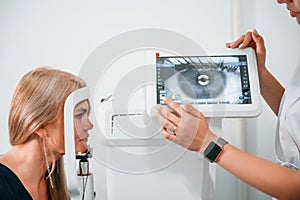 Side view. Woman`s vision is tested by clinic worker that using special device