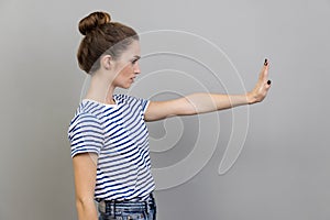 Side view of woman showing stop gesture, warning with raised palm, showing ban, block sign with hand