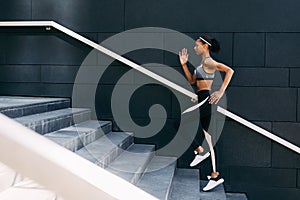 Side view of woman in sportswear running up the steps in the city