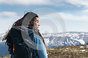 Side view of a woman standing looking at mountain landscape. Close - up