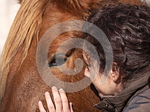 Side view of woman stroking a piebald pony