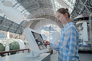 Side view: woman touching interactive touchscreen display kiosk at exhibition