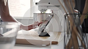 Side View Woman Using Touch Screen on a Digital Tablet In The Kitchen At Home