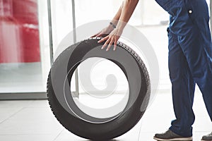 Side view. Woman walks with brand new wheel to the car. Conception of repair