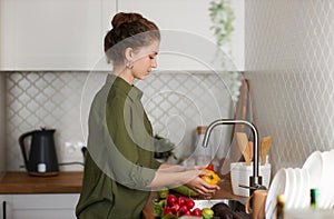 Side view woman washing fresh vegetables in kitchen