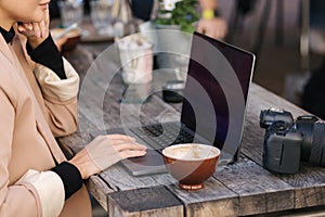 Side view of woman working on laptop in cafe outdoors. Stylisch freelancer drink coffee