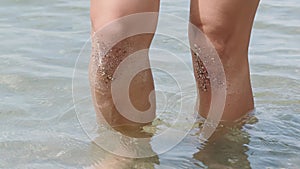 Side view, women legs knee deep in the lake, elegantly and gracefully goes, gently touching the surface of the water