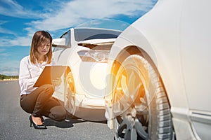 Side view of writing on clipboard while insurance agent examining car after accident